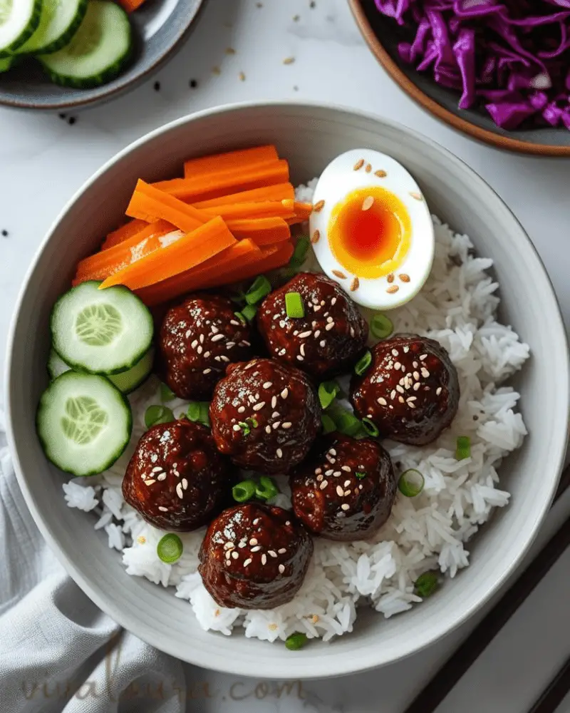 Close-up of sticky Korean BBQ glazed meatballs served with rice and colorful vegetables in a bowl 